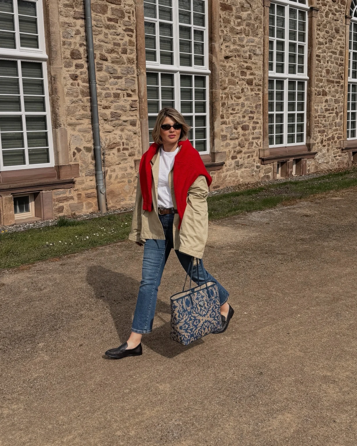 Lara walking past a brick building