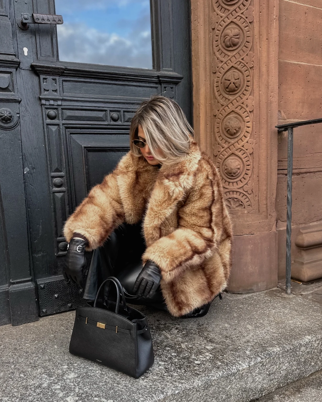 Lara with a black bag beside an ornate doorway